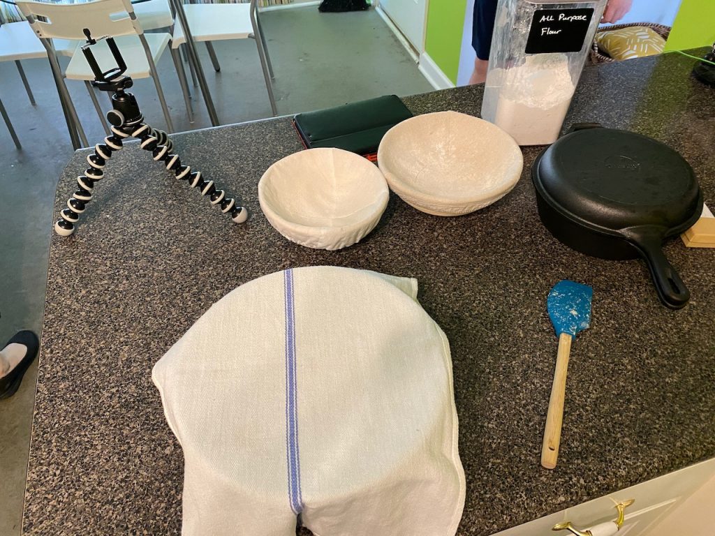 A tripod, bowl with a towl over it, spatula, two brotforms and a dutch oven on my kitchen counter