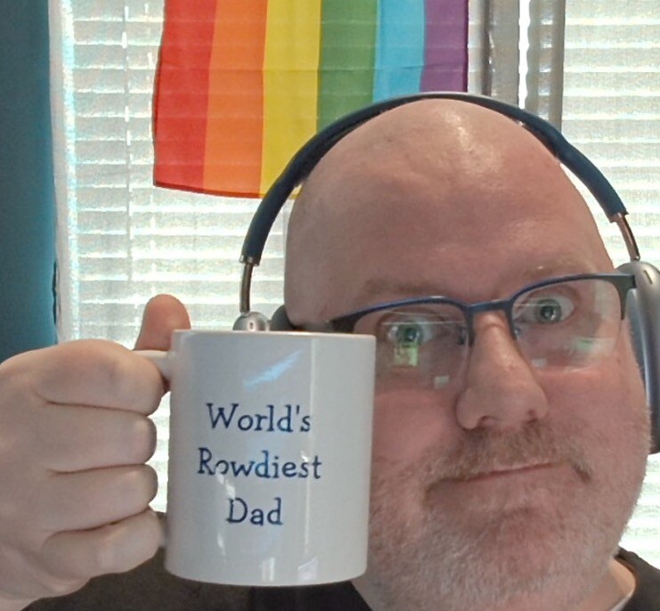 Me, a bald white man with a white beard, holding up my "World's Rowdiest Dad" mug while kind of smiling.