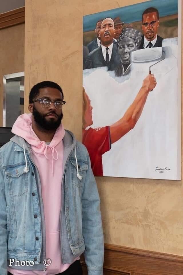Jonathan Harris next to his art depicting the whitewashing of Black history in America