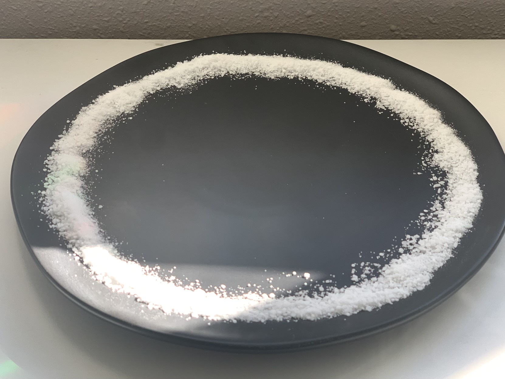 Black ceramic plate holding a ring of coarse salt.