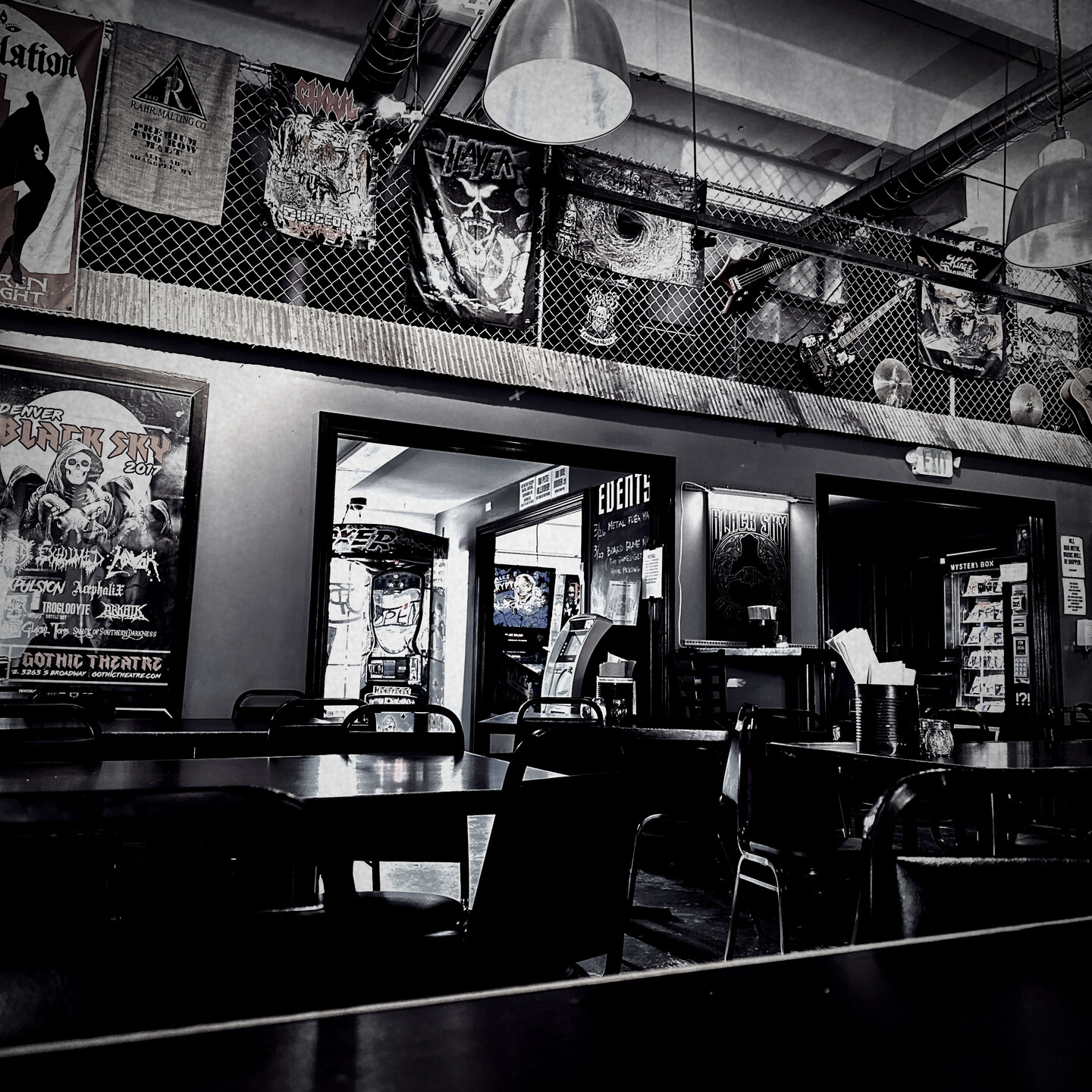 The entrance and wall of Black Sky Brewery - lots of metal posters, guitars and cymbals hanging from a chain link fence above the entry alcove. 