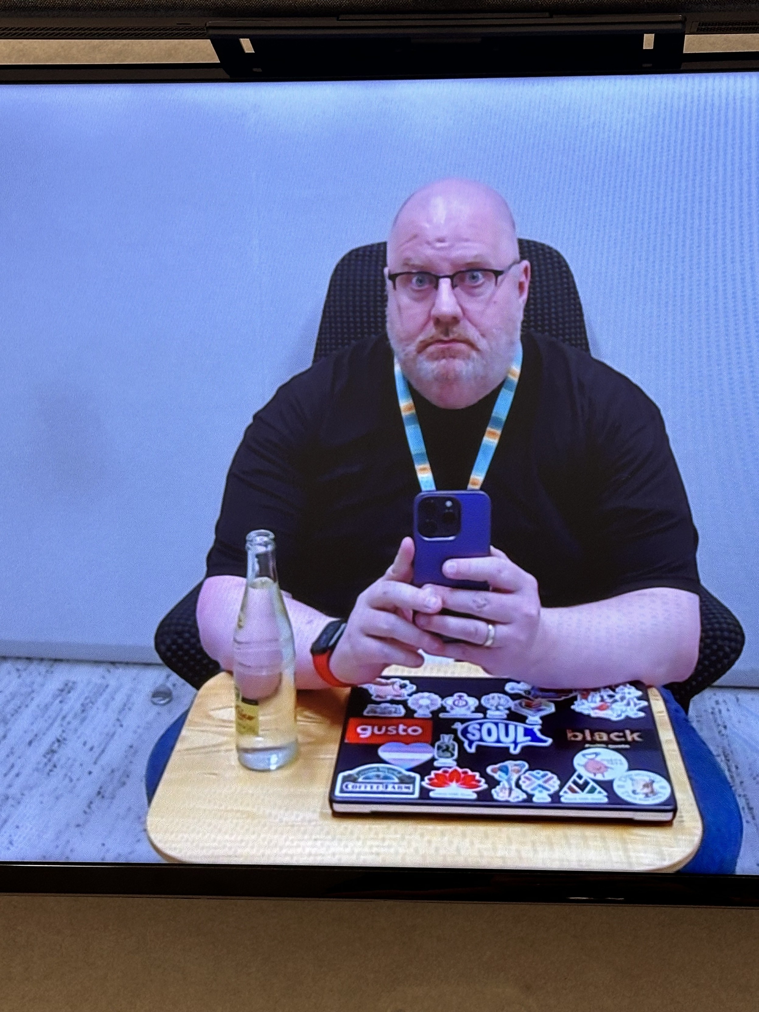 A photo of a bald tired man sitting in a meeting waiting for other people to show up. 
