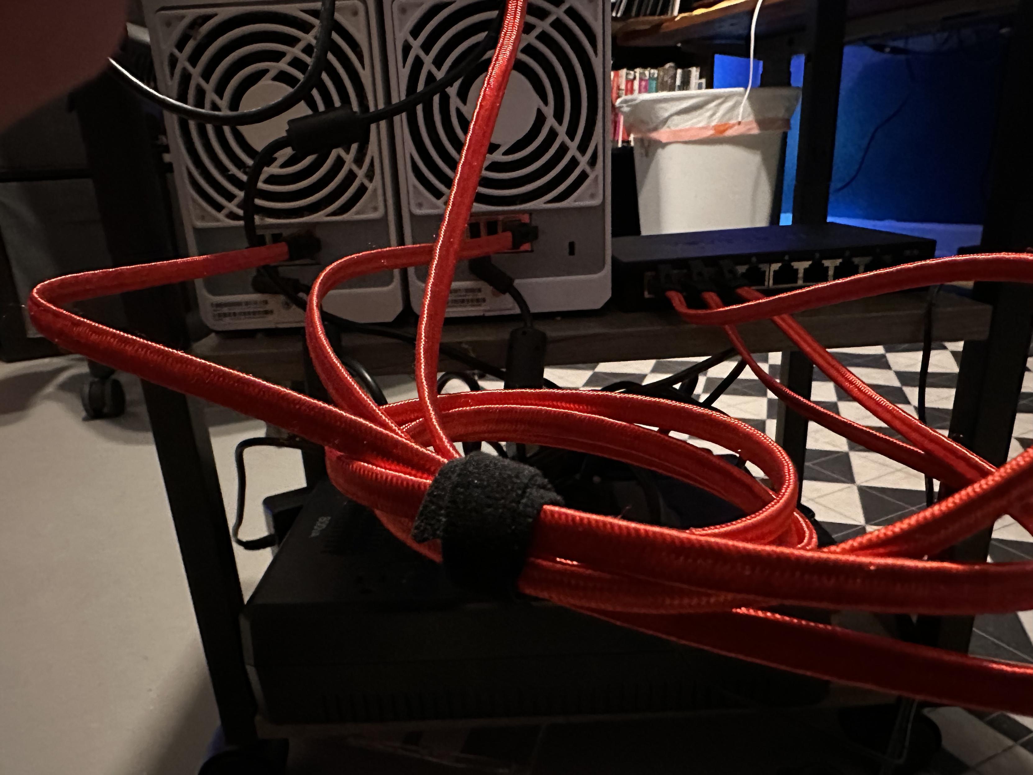 A phot of the back of two small NAS boxes, and a bundle of colorful networking cables wrapped with Velcro. 