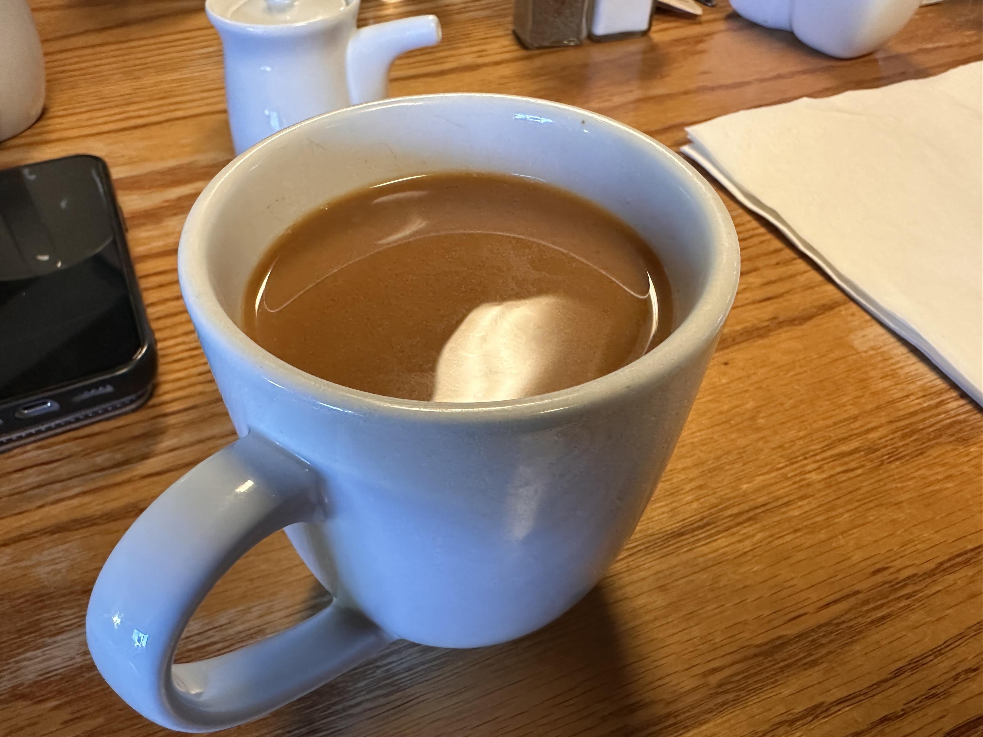 A diner cup of coffee on a wooden table. 