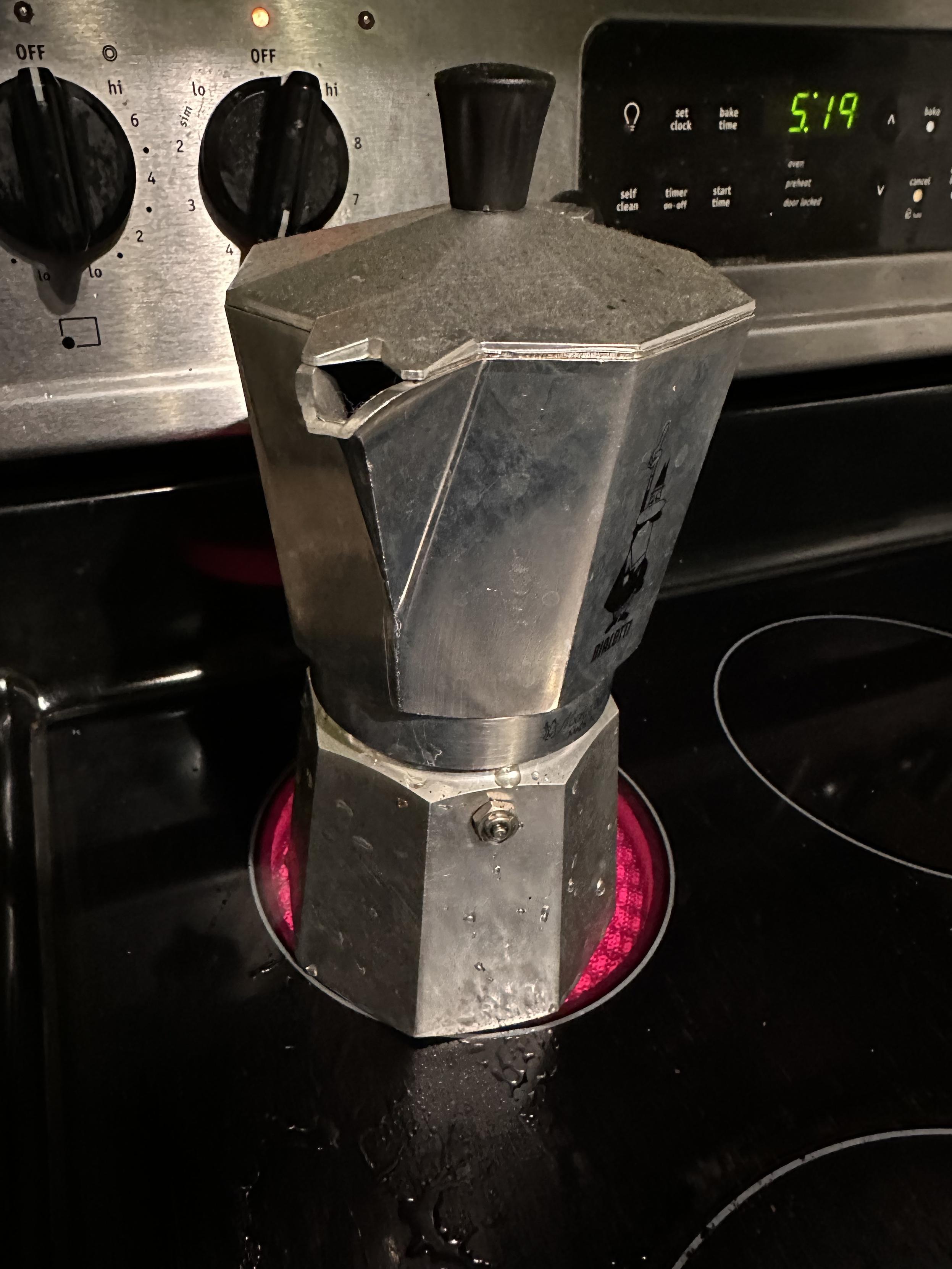 A moca espresso make on the stove, the heating element under it glowing red. 