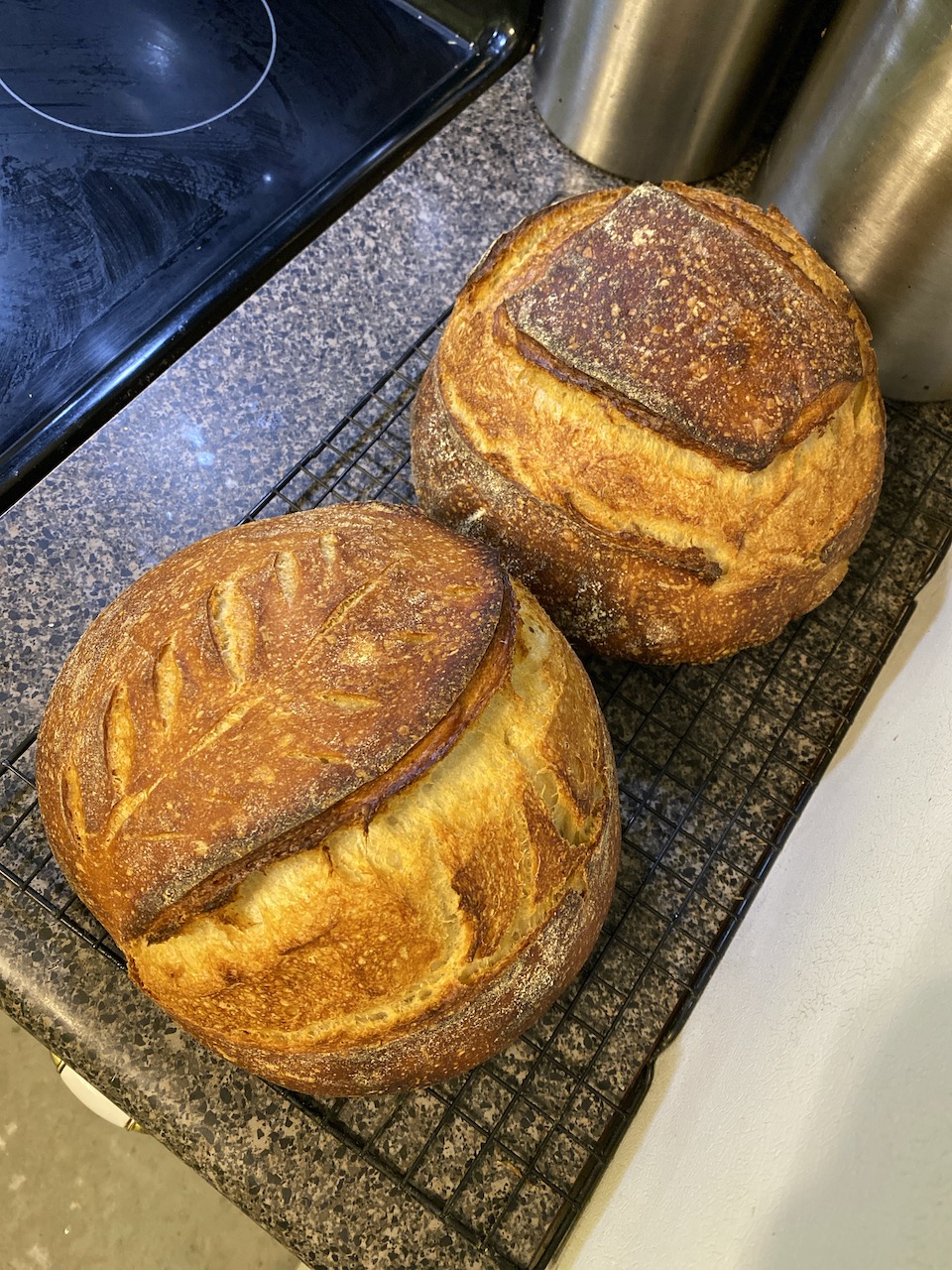 Two gorgeous loaves of pain au levain on a cooling rack.